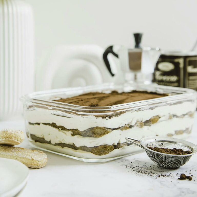 Beautiful layered tiramisu dessert with a coffee-focused setup, styled indoors in Riyadh.